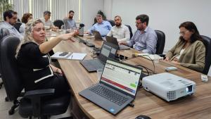 Foto da reunião, com todos os participantes reunidos em torno da mesa