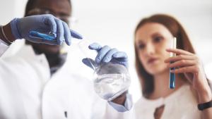 Um cientista negro e uma cientista branca em um laboratório químico fazendo um experimento