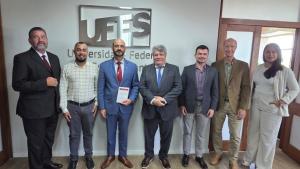 Foto dos participante da reunião em frente a uma parede onde está instalada a logomarca da Ufes